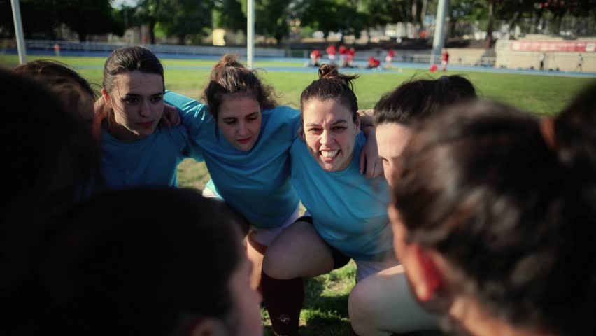 Determined female rugby players in blue jerseys huddling together on the field, showing unity and focus. Female Rugby Team Huddling for Motivation - Powered by Shutterstock - Get 15% off with code: PIKWIZARD15