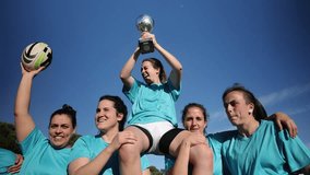Excited female rugby players lift a teammate holding a trophy, celebrating their victory with joyful expressions. Jubilant Female Rugby Team Celebrates Victory - Powered by Shutterstock - Get 15% off with code: PIKWIZARD15