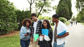 Multi-ethnic young students surfing with their mobile phones while walking around the university campus. Diverse students laughing and chatting outdoors on campus, holding notebooks - Powered by Shutterstock - Get 15% off with code: PIKWIZARD15