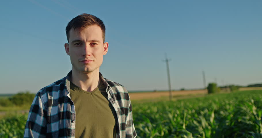 Portrait of an attractive young farmer against a rural landscape, looking at the camera