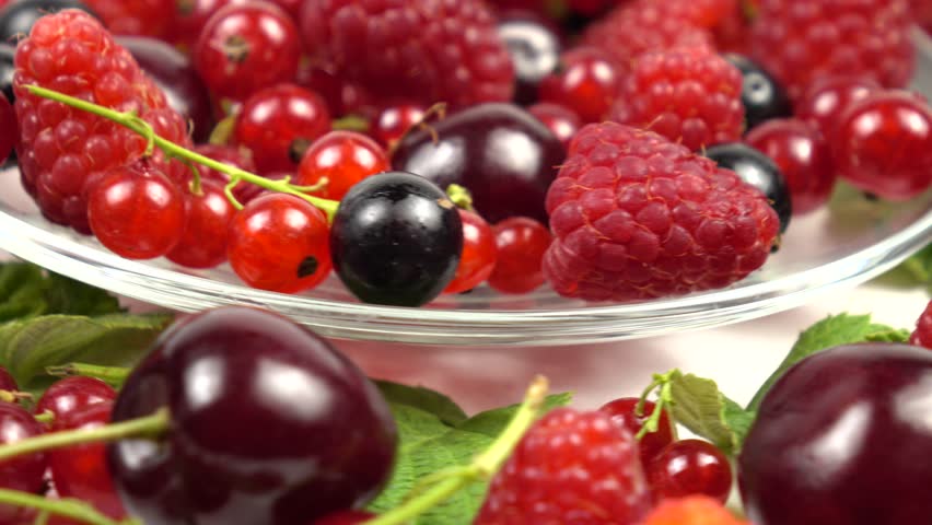 Fresh red and black currants, cherries and ripe raspberries on a white board. Vitamin set of berries and fruits