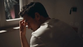 Guy looking dark window bedroom showing deep contemplation closeup. Sad sleepless man sitting dark apartment bed alone. Thoughtful male feeling solitude having sleep problem. Mental health concept. - Powered by Shutterstock - Get 15% off with code: PIKWIZARD15
