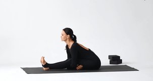 A sports video blogger shows how to perform a variation of the Paschimottanasana exercise, a seated asana with a forward bend, clasping your legs - Powered by Shutterstock - Get 15% off with code: PIKWIZARD15