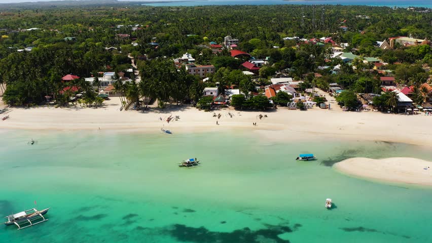 Aerial view of white sandy beach with boats floating on transparent turquoise sea water and waves. Bantayan Island. Cebu, Philippines.