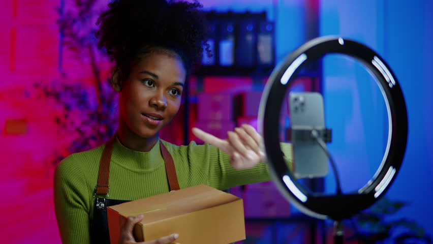African online seller is live streaming broadcast for selling new products in parcel boxes and receiving the orders from customer via smartphone and tablet on shopping online application.