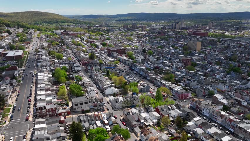 High angle flight over american town with green mountains landscape in background. Street with driving cars in spring season. Reading, Pennsylvania, USA. Drone birds eye shot.