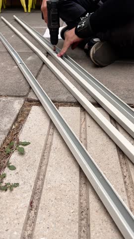 Drilling metal tubes: young man using an electric drill in the back garden