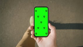 POV shot Caucasian man looking at chroma key phone in his hand walking city street. Smart phone green screen in hand. Walk with cellphone, application mock up, camera locked on motion tracking markers - Powered by Shutterstock - Get 15% off with code: PIKWIZARD15
