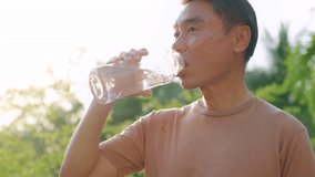 Asian elderly sportsman drinking water while running exercise in garden. Attractive mature older man jogger taking a break after practice workout warm up for health care in public park during sunset. - Powered by Shutterstock - Get 15% off with code: PIKWIZARD15