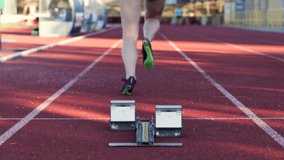 A rear view of a female athlete, ready to run at the starting point of an athletics track. - Powered by Shutterstock - Get 15% off with code: PIKWIZARD15