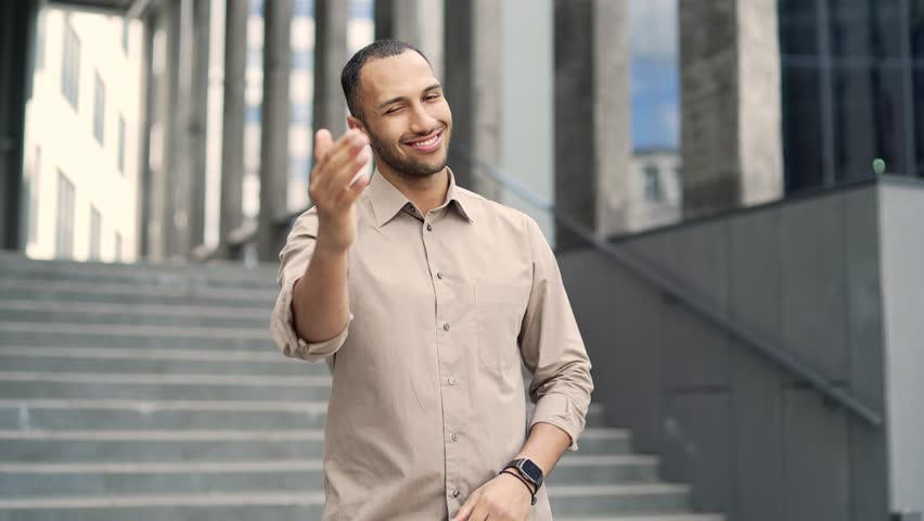 Happy young businessman invites you to join the team near the entrance to the business office building. Employee, hr entrepreneur, man employer investor calls to invest or hiring look at camera Join U