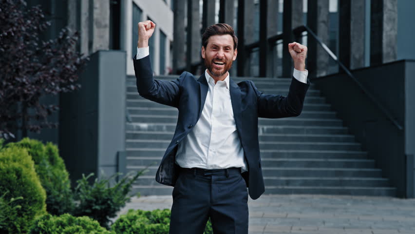 Happy satisfied caucasian man customer male businessman winner celebrating victory rejoice in achieving success outdoors in city near office promotion at work good result winning scream with happiness