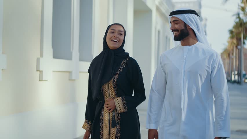Cinematic image of a young couple from the united arab emirates spending time outdoor. Man and woman with traditional emirati kandura and abaya in Dubai.