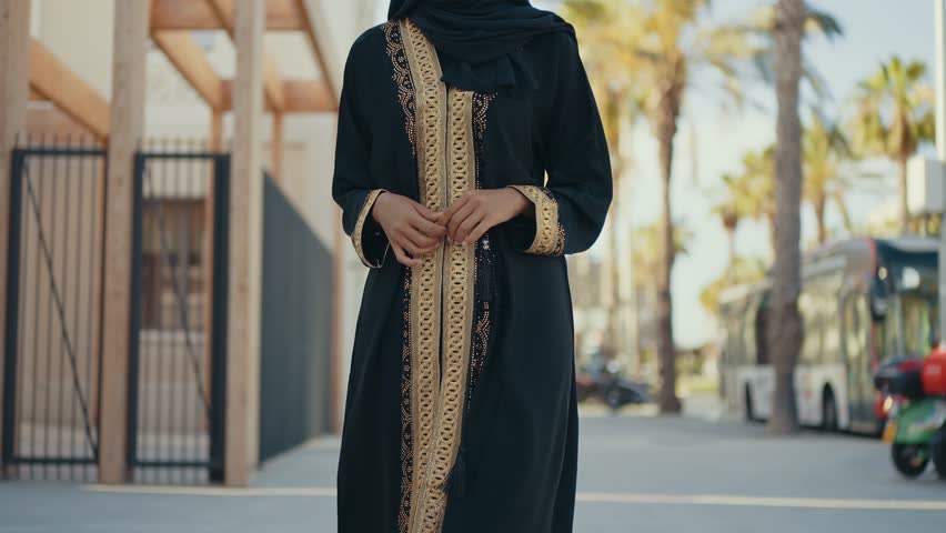 Cinematic image of a beautiful woman from Dubai wearing black abaya dress and walking in the city center and doing shopping.