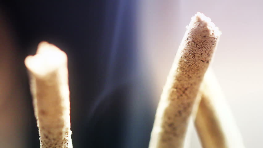 Close up of burning incense sticks with smoke over black background