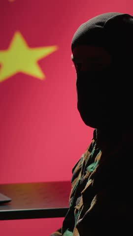 Vertical video Chinese terrorist using software algorithms on laptop to do fundamentalism propaganda on internet. CCP government secret agent wearing mask sharing dangerous illegal malware online