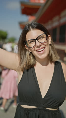 Joyful hispanic woman with open arms, embracing freedom on kyoto's streets, carefree smile framed by glasses lending charm to her beauty