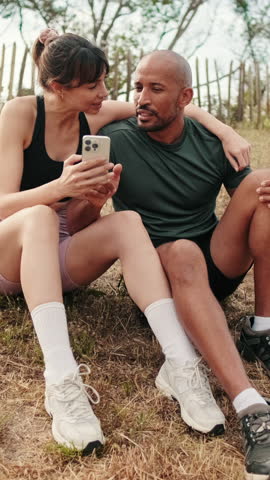 Vertical video, Multi-ethnic beautiful fit girl and strong man staring into a phone screen. A video call or watching a video online. Modern technology and relationships, social media content