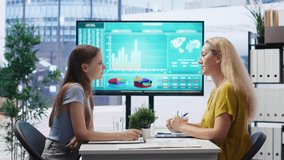 Financial advisor showing data graphs on big screen to customers, analyzing market trends to do forecasting. Mom and gen Z girl checking investment plan on display made by agent, camera B - Powered by Shutterstock - Get 15% off with code: PIKWIZARD15