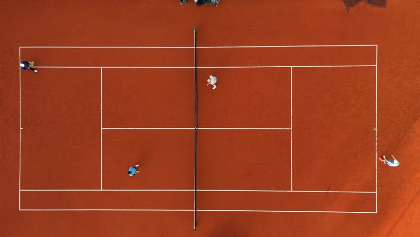 People playing a doubles tennis match. Top steady aerial camera