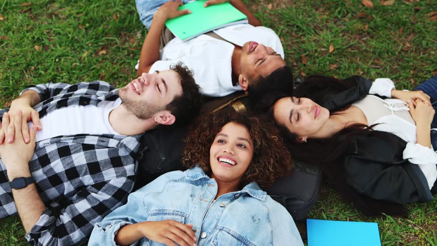 Students bonding on grass, laughing and connecting outdoors.    Diverse students bonding and laughing on grass, fostering friendship outdoors