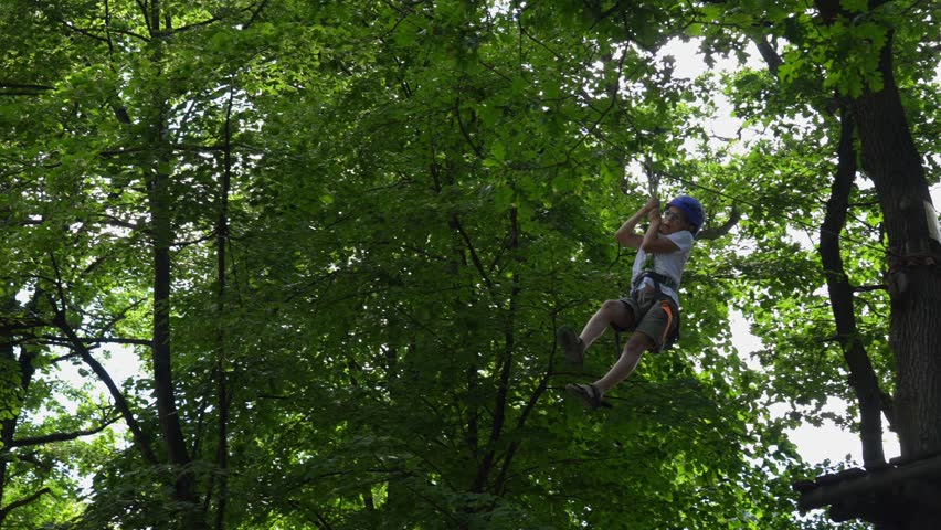 Boy in a rope park makes a bungee jump and flies on a carabiner. Active lifestyle. Rope park in the forest. Time in the fresh air. High quality 4k footage