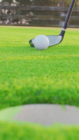 VERTICAL VIDEO. Male hand in a golf glove puts the ball on the field. Golfer placing golf ball on the tee at golf course. Close up