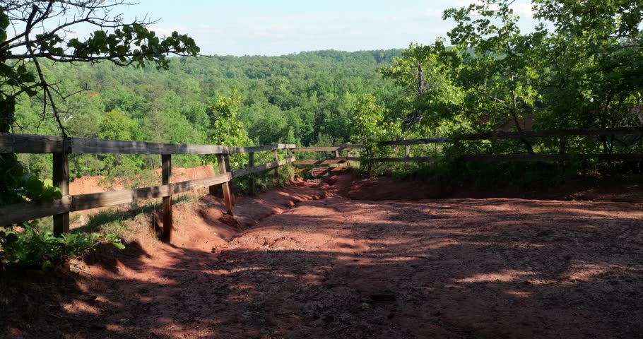 Clay hiking trail and fences leading to danger sign overlooking canyon at Providence Canyon State park in Lumpkin Georgia viewed on sunny spring day.