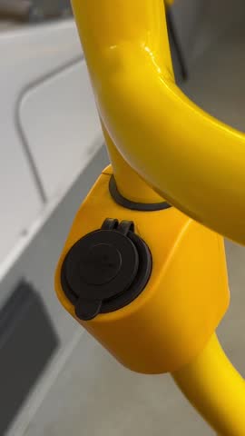 Vertical close up video. Man opens plug and inserts USB cable into socket. Charger for mobile devices, phones and smartphones on yellow handrail in bus. Male hand. Modern urban accessible environment