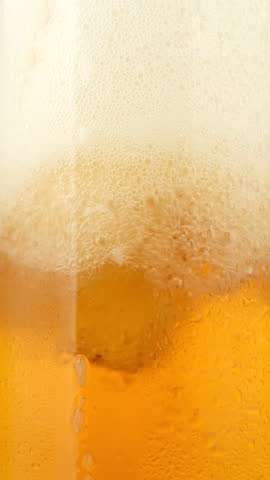 Pouring Cold beer with foam in glass, macro