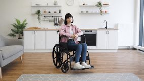Young woman in wheelchair sitting in bright modern kitchen, looking thoughtful. Comfortable and stylish interior with decor, plants, and modern appliances. - Powered by Shutterstock - Get 15% off with code: PIKWIZARD15