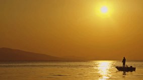 Fisherman Fishing with a Fishing Rod in a Boat in the Ocean at Yellow Sunset Footage. - Powered by Shutterstock - Get 15% off with code: PIKWIZARD15
