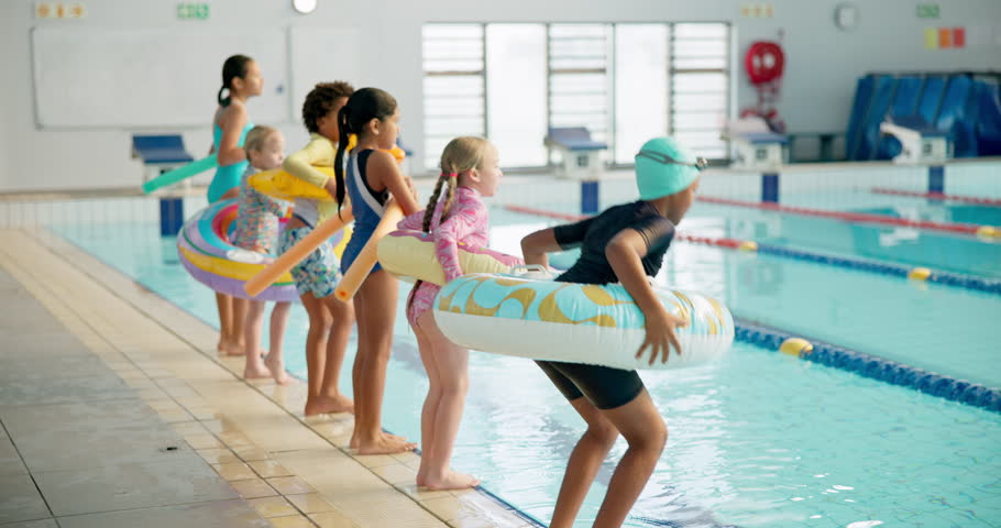 Kids, happy and jump in swimming pool with floatie for lesson in centre with swimsuits for recreation. People, friends and diversity with smile or excited for workout and training with sport