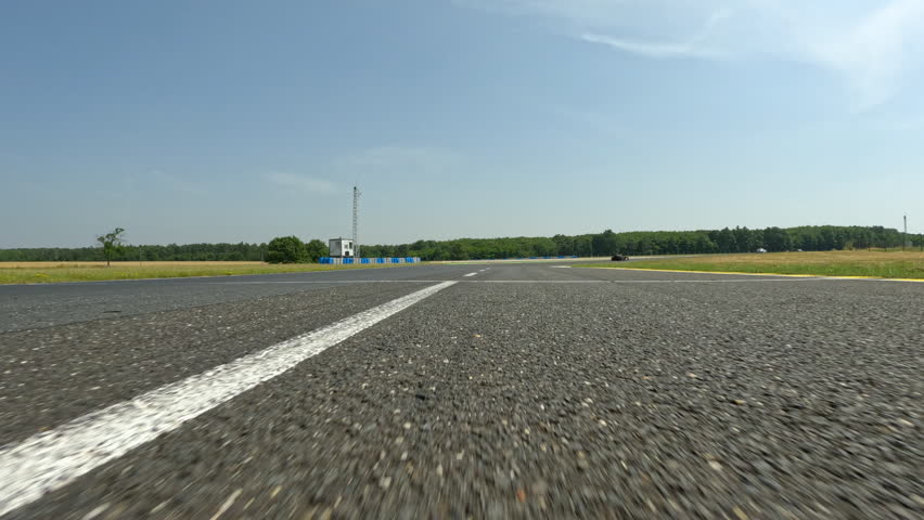 POV: Chasing the race leader on during an adrenaline filled automotive race in the sunny countryside. Speeding around the corners of a race circuit, chasing the car ahead. Amateur motorsport racing
