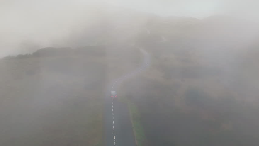 Car moving in cloudy mountains road in low clouds and fog on Madeira island. Transportation, car rental, insurance concept