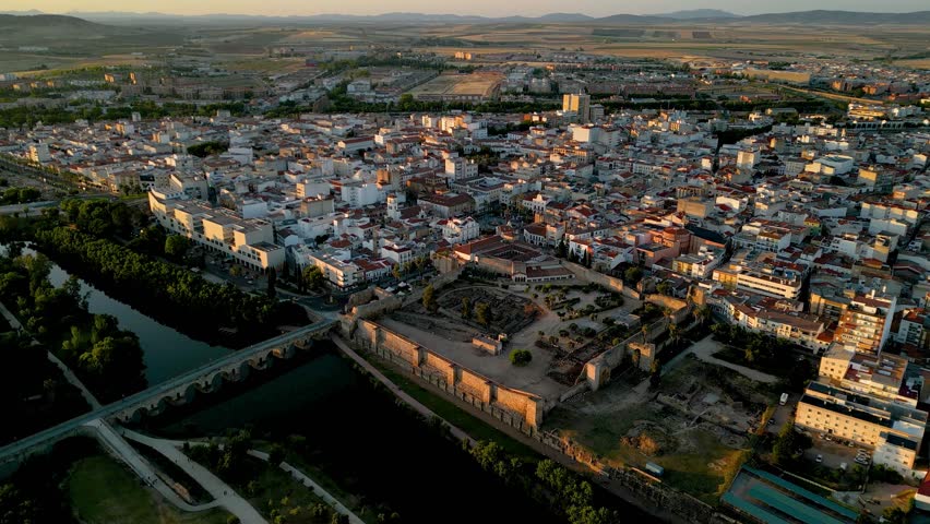 Spectacular aerial footage of Merida city at sunset. Beautiful warm colours reflecting on buildings. Famous travel destination in Badajoz Province, Spain. View of Alcazar of Merida and historic city