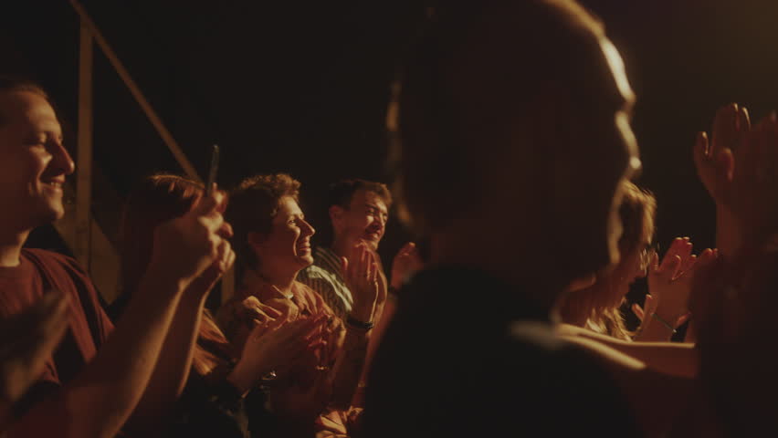 Young cheerful people in audience laughing and applauding to African American comedian performing on stage in stand-up club