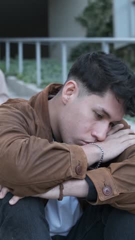 A group of students bulling an hispanic man sitting on the stairs outdoors