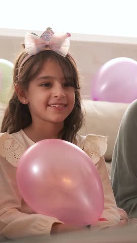 Girl blowing out the candles on her birthday cake sitting on a sofa