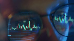 Trader wearing glasses is working on laptop computer. Screen with stock market charts and Bitcoin BTC or Ethereum ETH data analysis reflection. Broker trading online. Altcoins crypto currency trading - Powered by Shutterstock - Get 15% off with code: PIKWIZARD15