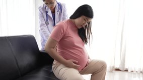 An Asian female doctor and nurse on a sofa provide medical care to a pregnant woman, using ultrasound and stethoscope, and offering massage for relief from backache, waist pain, and shoulder pain. - Powered by Shutterstock - Get 15% off with code: PIKWIZARD15