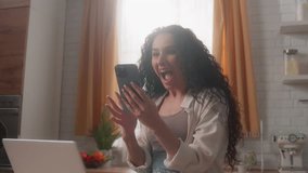 Happy excited Hispanic girl Latina woman female rejoice celebrate win mobile phone offer message victory achievement winning yell shouting at home kitchen with laptop smartphone success discount app - Powered by Shutterstock - Get 15% off with code: PIKWIZARD15