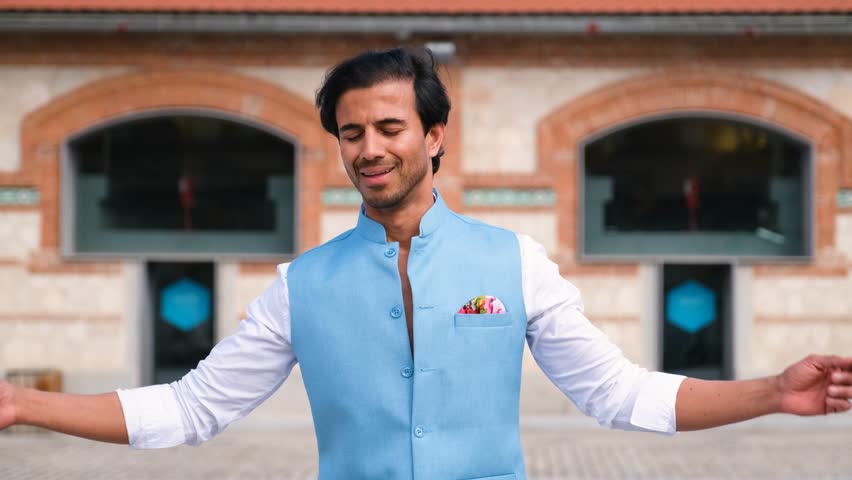 Young indian man dancing in the street wearing colorful clothes