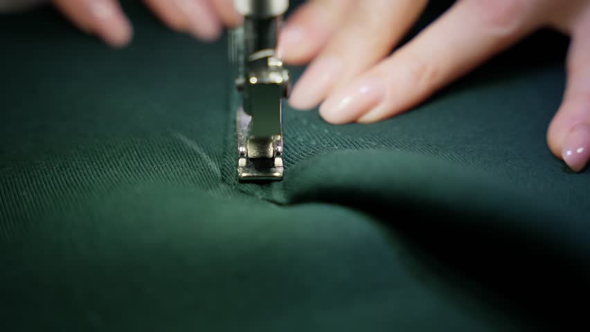 Hands of seamstress sew clothes on fabric. Clothing detailing concept.