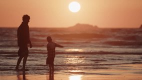 Father and son bonds together on beach at sunset throwing rocks into shallows - Powered by Shutterstock - Get 15% off with code: PIKWIZARD15