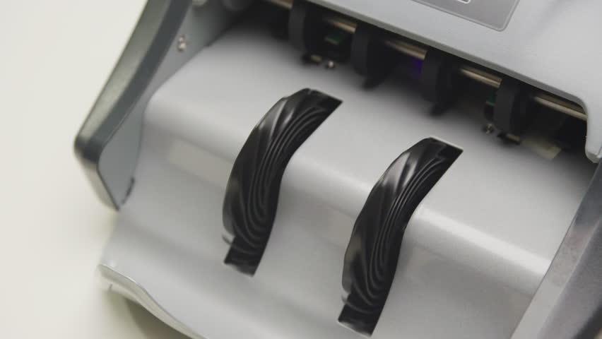 Close-up view of a cash counting machine processing hundred dollar bills in motion