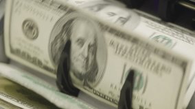 Close-up view of a cash counting machine processing hundred dollar bills in motion - Powered by Shutterstock - Get 15% off with code: PIKWIZARD15