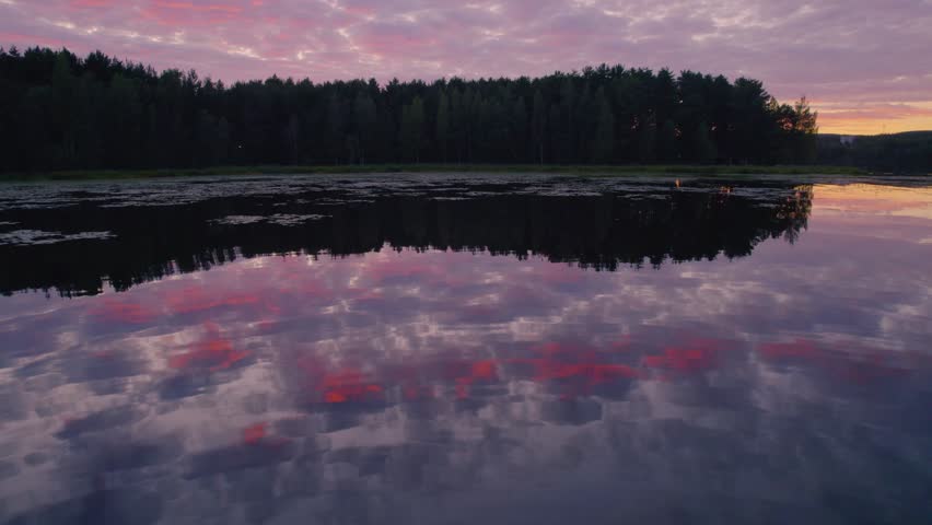 Sunset over a peaceful lake during the summer in Sweden. Shot with a drone.