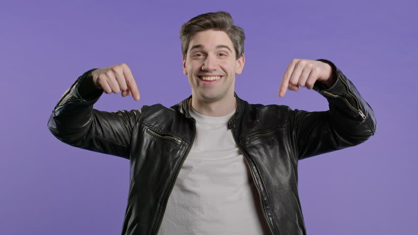 Blogger man pointing down advertising area. Violet background. Click, subscribe