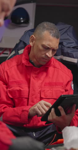 Tablet, paramedic and a man in an ambulance for emergency service or professional accident rescue. Technology, research and information with a first aid emt looking at an online medical report